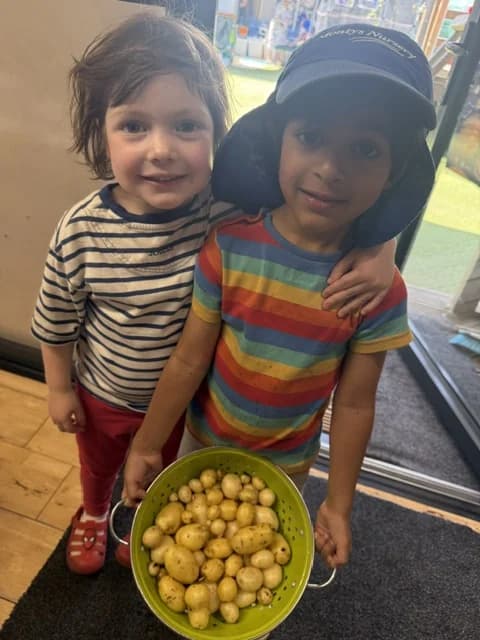Two children holding a colander of potatoes harvested at Montys Nursery