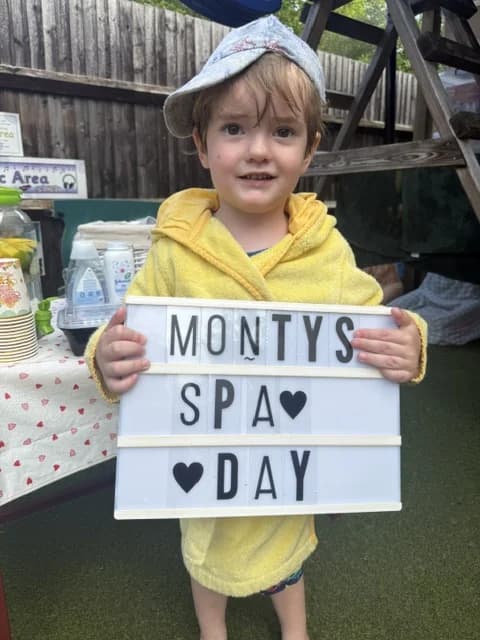 Child at Montys Spa Day holding a light-up sign in the nursery garden